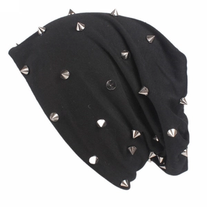 Détail du bonnet noir en tricot avec des rivets métalliques punk sur fond blanc neutre