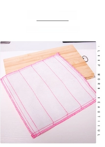 Close-up of multi-layer white cotton dishcloth with red stitching on a wooden board
