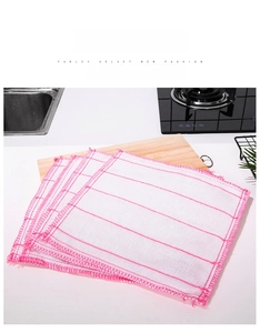 Macro detail of multi-layer white grid dishcloth with pink stitched edges on wooden board