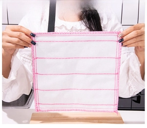 Detail of a white square dishcloth with pink stitching held over a kitchen sink