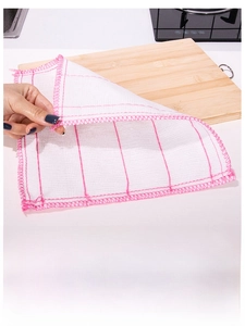 Macro detail of multi-layer white cleaning cloth with pink stitching on wood board