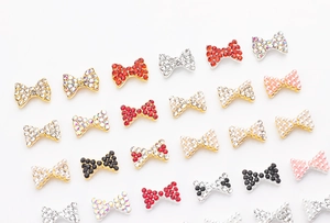 Gros plan de bijoux d'ongles en forme de nœud avec strass rouges et perles sur blanc