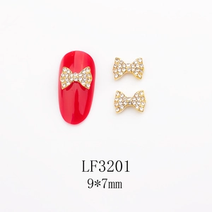 Vue macro de nœud doré pour nail art avec strass blancs sur ongle rouge, 9x7mm