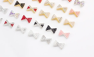 Vue macro de nœuds nail art en métal avec strass rouges et perles de nacre blanches