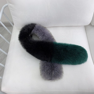Luxurious multi-color fox fur scarf in black, grey and green displayed on a white chair