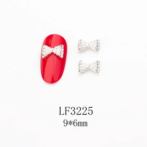 Vue détaillée du bijou d'ongle nœud 9x6mm avec alliage argenté, perles blanches et strass