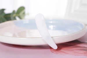 Close-up of white curved facial massage scraper and gua sha tool for personal skincare