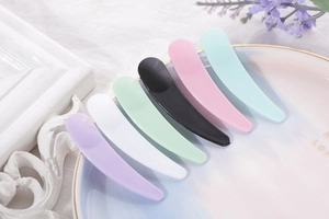 Macro detail of six colorful curved plastic cosmetic spatulas on a decorative plate
