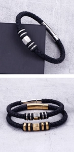 Detail of woven black leather bracelets with metallic charms and Buddhist engraving