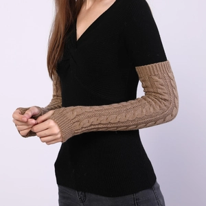 Detail of brown cable knit arm warmers showing thick braided texture and ribbed cuffs