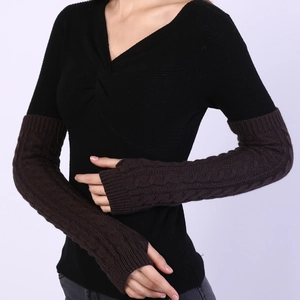 Detail of dark brown cable-knit arm warmers showing the textured knit and thumb hole