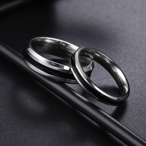 Macro detail of brushed stainless steel couple rings with black enamel inlay stripes