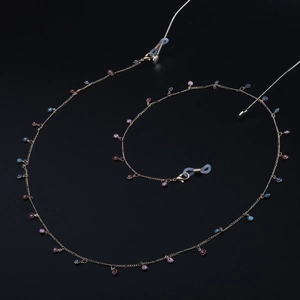 Golden chain eyewear strap featuring colorful evil eye charms on a solid black background