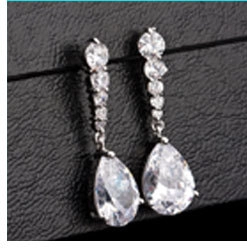 Macro shot of pear-shaped zircon tassel earrings with silver finish on black leather