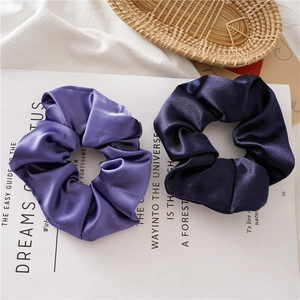 Detail of silk satin scrunchies in light purple and dark navy blue on a magazine