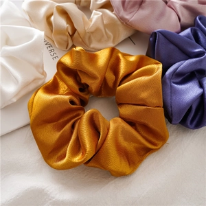 Close-up of elegant silk satin scrunchies in multiple colors with a soft glossy texture