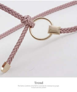 Detailed close-up of pink braided belt featuring a gold round buckle and metallic tip