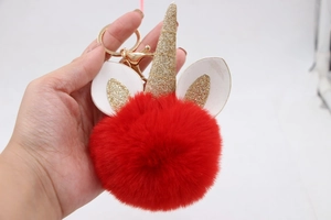 Detail of red plush unicorn keychain with gold glitter horn and metallic gold hook
