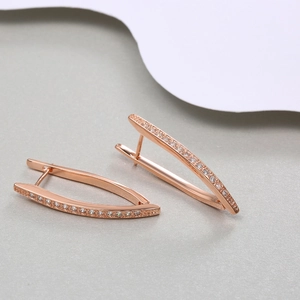 Macro shot of rose gold hoop earrings with pave-set cubic zirconia on a smooth surface