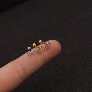 Dreifarbige Edelstahl-Ohrstecker mit klaren Zirkonia-Steinen auf einem Finger