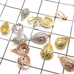 Macro detail of hollow teardrop and heart jewelry charms in gold, silver, and rose gold