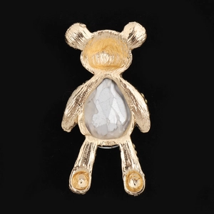Golden bear-shaped accessory with white resin drop center and textured metal back