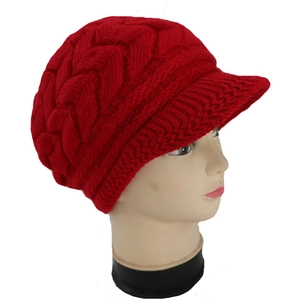 Dettaglio del cappello in maglia a trecce rosso con visiera e trama spessa
