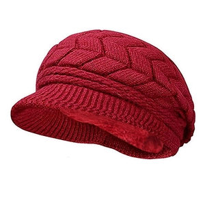 Dettaglio della fodera in pile e maglia a trecce su berretto invernale rosso con visiera