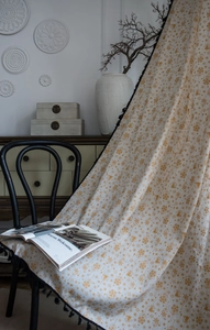 Close-up of golden snowflake and bell patterns on cream cotton linen window curtain