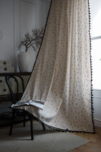Detailed texture of beige cotton linen curtain with gold geometric patterns and black tassels