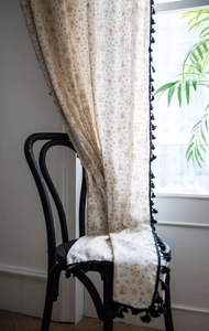Detail of beige cotton linen Christmas curtain with gold foil patterns and black fringe