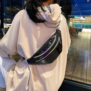 Close-up of stylish black glossy waist bag with silver zipper and white strap on model