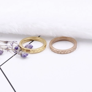 Minimalist hammered titanium steel pinky rings in gold and rose gold on a white surface