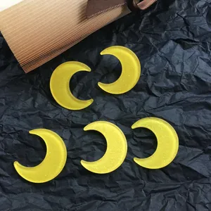 Five yellow glitter crescent moon acrylic charms for DIY jewelry on a black background