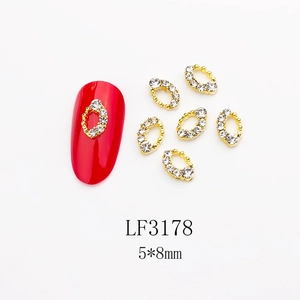 Macro view of gold alloy nail art charm LF3178 with rhinestones on a red manicure