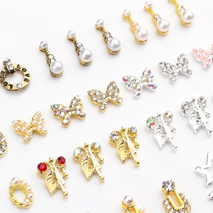 Macro shot of assorted butterfly nail charms with pearls and rhinestones on white background