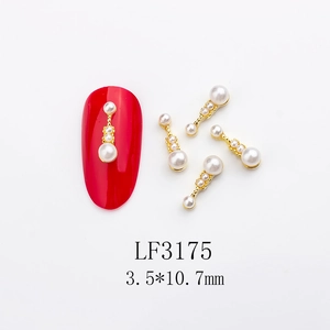 Macro shot of LF3175 gold nail charms with white pearls beside a red manicure sample