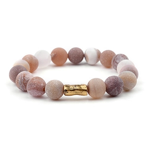 Dettaglio macro delle perle in pietra naturale e del tubo di ottone dorato del bracciale