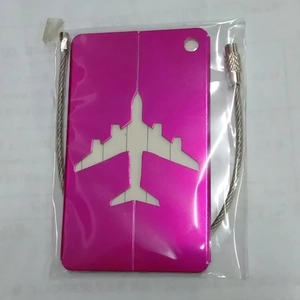 Detail of rose red metal luggage tag with airplane cutout and steel wire loop