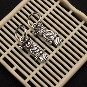 Macro view of two vintage silver owl charms with detailed feathers and alloy texture