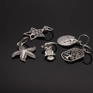 Detailed view of 5 vintage silver alloy charms featuring owl, starfish and shell motifs