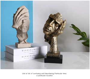 Detail of abstract face sculptures in sandstone and gold finish on book props