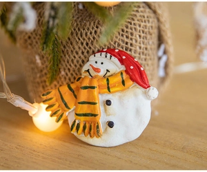Macro shot of 3D snowman magnet with red hat and scarf on a festive rustic wooden desk