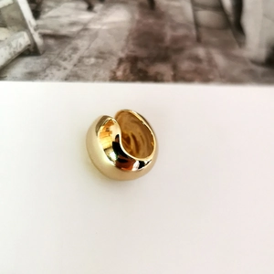 Macro shot of minimalist gold spherical ear cuff with a polished metallic finish