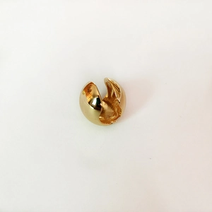 Macro shot of polished gold spherical ear cuff with a glossy C-shaped geometric design