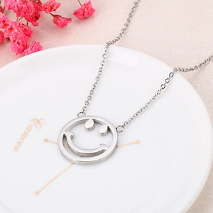 Collier minimaliste argenté avec pendentif smiley sur un plateau à bijoux décoratif