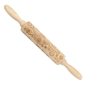 Detailed view of wooden rolling pin with engraved snowflake and swirl patterns for baking