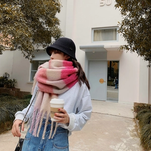 Detail of pink and beige rainbow plaid scarf with long tassels and black bucket hat