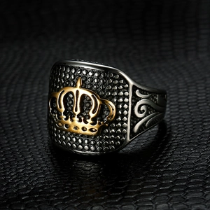 Close-up of silver steel signet ring with a gold crown relief on black leather