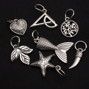 Close-up of vintage silver alloy charms featuring heart, starfish, and leaf designs